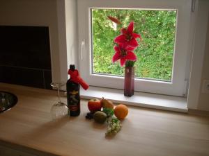 eine Vase mit einer roten Blume und Obst auf dem Tisch in der Unterkunft Haus Königsstieg in Struckum