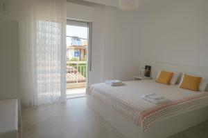 a white bedroom with a bed and a large window at Balcony Sea Hanioti Stay in Hanioti