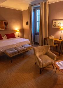 a bedroom with a bed and a chair and a window at Hôtel de Mirmande in Mirmande