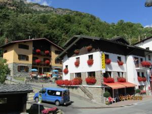 a building with flowers on the windows and a blue van at Hotel Punta Cian in Valtournenche