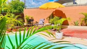 a patio with chairs and an umbrella and plants at Modern House with Pool in Grand-Baie