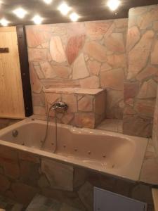 y baño con bañera y pared de piedra. en Chez Plaschy, en Salgesch