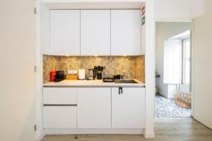 a kitchen with white cabinets and a sink at Alma da Vida Ferragudo in Ferragudo