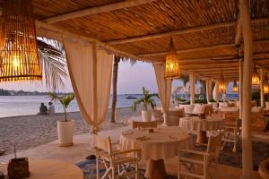 a restaurant on the beach with tables and chairs at The Majlis Resort in Lamu