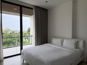 a bedroom with a bed and a large window at The 211 Rayong in Ban Phlong Sawai
