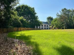 a large grass field with a house in the background at MH Hôtel & Spa Arradon - Golfe du Morbihan in Arradon
