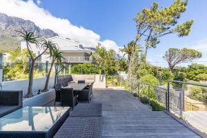 a patio with a table and chairs and trees at The Crystal Apartments in Cape Town