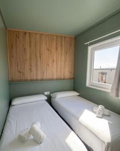two beds in a small room with a window at Somo Bungalow Resort - Camping Latas in Somo