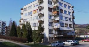 a tall white building with cars parked in front of it at Relax Visoko Apartman in Visoko