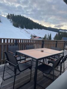 a wooden table and chairs on a deck with snow at Chata Barvinok in Litmanová