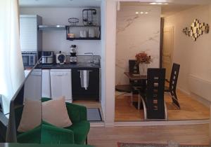 a living room and kitchen with a green couch and a table at L'Écrin Appart in Villedieu-les-Poêles