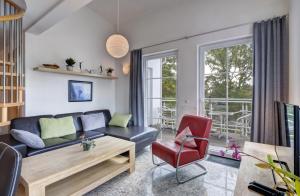 ein Wohnzimmer mit einem schwarzen Sofa und einem roten Stuhl in der Unterkunft Ostseeresidenz Gorki- Park - 23 mit Wellness und Schwimmbad in Bansin