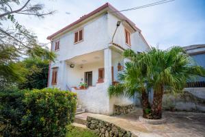 a white house with a palm tree in front of it at VILLA SEA VIEW IN SICILY, Real Relax in Fontane Bianche