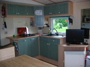 a kitchen with green cabinets and a television in it at Ty Bihan de L'Aber in Crozon