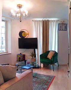a living room with a couch and a green chair at L'Écrin Appart in Villedieu-les-Poêles