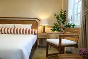 a bedroom with a bed and a chair and a desk at La Villa des Chien in Ban Nong Chap Tao