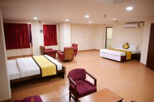 a hotel room with two beds and a chair at WoodLand Suites in Cochin