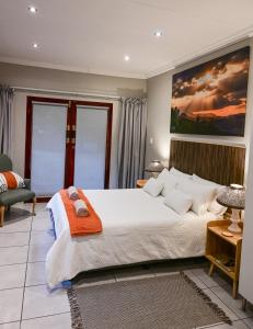 a bedroom with a large bed with an orange blanket on it at Son Heuwel B&B room in Nelspruit