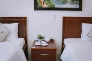 a bedroom with two beds and a nightstand with cups on it at Nhà Khách CF15 in Danang