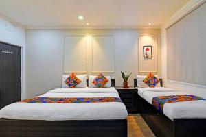 a bedroom with two beds with colorful pillows at FabHotel Demattrie Budget in Kolkata +20 photos
