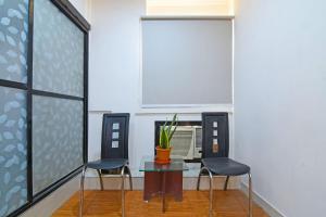 a room with two chairs and a table with a plant on it at FabHotel Demattrie Budget in Kolkata