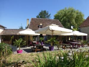 a patio with tables and umbrellas in front of a building at Camping Les Terrasses de Dordogne in Rouffignac Saint-Cernin