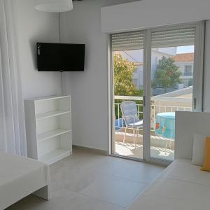 a living room with a tv and a sliding glass door at Balcony Sea Hanioti Stay in Hanioti