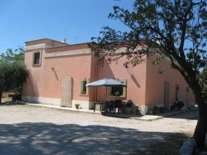 ein Gebäude mit einem Tisch und einem Sonnenschirm davor in der Unterkunft Villa Rita Bed & Breakfast in Campi Salentina