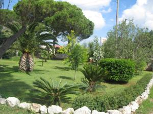 um jardim com palmeiras e uma parede de pedra em Villa Rita Bed & Breakfast em Campi Salentina