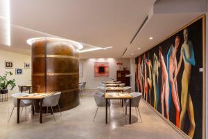 a restaurant with tables and chairs and a large painting at Hotel La Rovere in Rome
