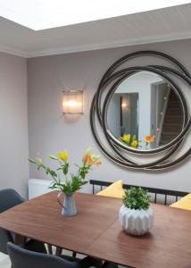 a dining room table with a round mirror on the wall at Albero Apartment in Eyemouth