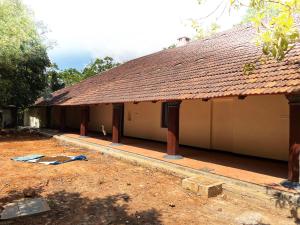 a building with a brown roof and a dirt yard at Colonial canopy in Suntikoppa