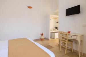 a bedroom with a bed and a desk and a television at Masseria il Vignale in Ostuni