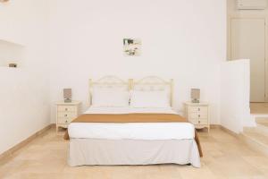 a white bedroom with a large bed and two night stands at Masseria il Vignale in Ostuni