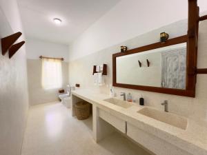 a bathroom with a sink and a mirror and a toilet at Villa Gladys in Watamu +15 photos