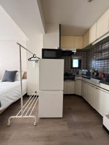 a small kitchen with a bed and a white refrigerator at サムティ扇町 in Osaka