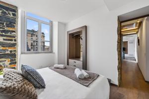 a white bedroom with a bed and a mirror at Appartamento Porta Torre - Porta Torre-Centro in Como