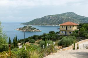 a house on a hill next to a body of water at Olympia House in Vathi