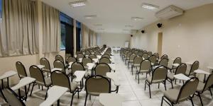 a room with rows of chairs in a classroom at Mirante Hotel in Governador Valadares