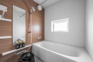 a bathroom with a white tub and a window at Grandia 302 in Sapporo