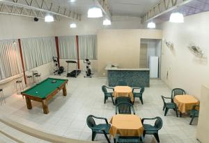 a pool table in a room with tables and chairs at Mirante Hotel in Governador Valadares
