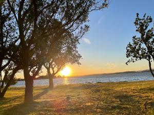 a picnic table on a beach with the sunset in the background at Lake Macquarie holidays in Marks Point