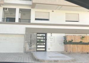 a white building with a door and a balcony at Le gris Perle in Sfax