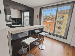 a kitchen with a counter and stools in front of a window at Comfortable 1BR flat at great location - Baron 44 in Zurich +3 photos
