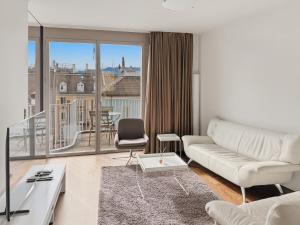 a living room with a white couch and a large window at Comfortable 1BR flat at great location - Baron 44 in Zurich