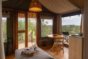 a room with windows and a table and a table and chairs at The Maa Guest House in Talek
