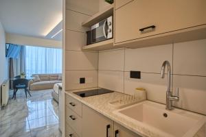 a kitchen with a sink and a living room at Marianna Hotel Apartments in Limassol +103 photos