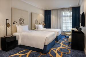 a hotel room with two beds and a television at Sofitel Shahd Al Madinah in Medina +104 photos