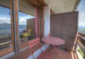 a balcony with a table and two chairs and a window at Antares 403 au centre a Anzere in Anzère +2 photos