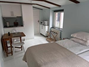 a bedroom with a bed and a table and a kitchen at Tiny flat - in medieval Ystad in Ystad